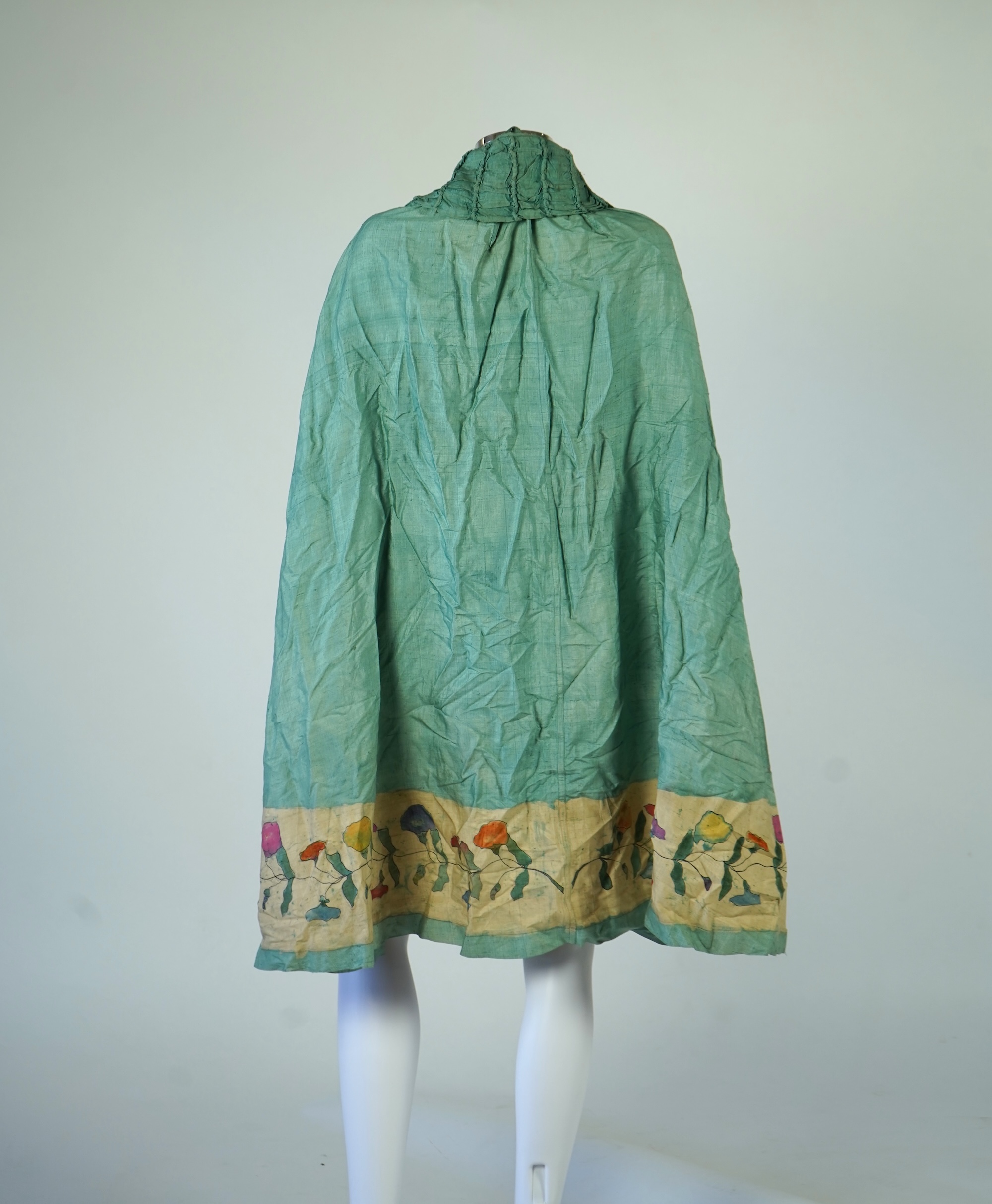 A 1920’s light green silk evening cape with hand batik borders and label: Tito de Canival Mode, together with a navy ladies two piece suit and a maroon satin evening dress. Cape 100cm long. Condition - cape good, navy tw